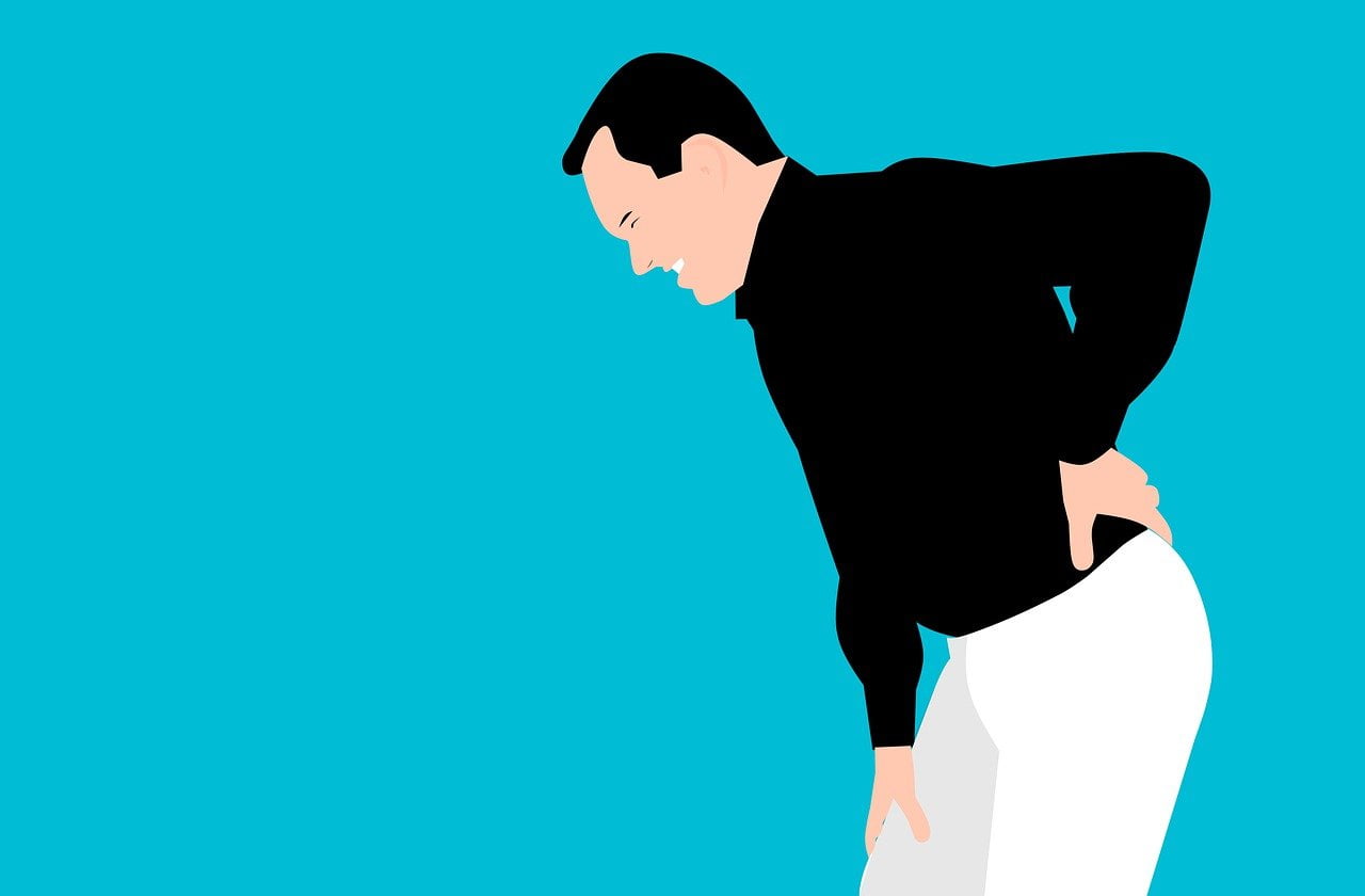 Illustration of a person in a black shirt and white pants holding their lower back and bending forward in pain, against a bright blue background.