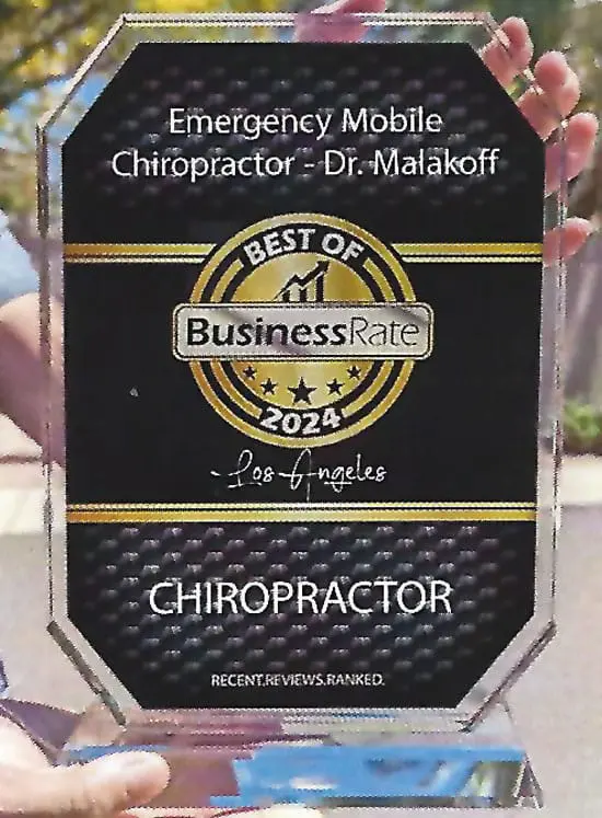 Hands holding a glass award plaque that reads: Emergency Mobile Chiropractor – Dr. Malakoff, Best of Business Rate 2024, Los Angeles, Chiropractor, Recent Reviews. Ranked.